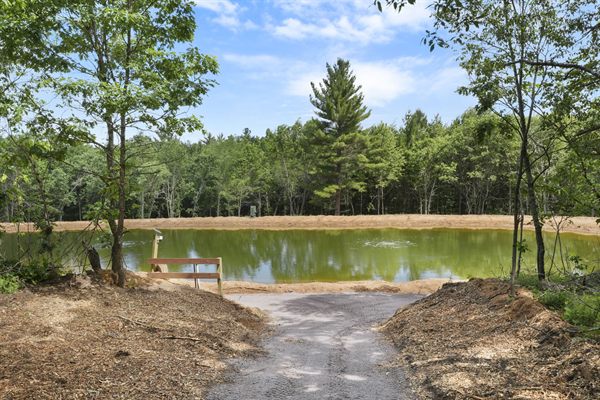 Aerial view of Oak and Ember cabins, pond, and wooded acreage