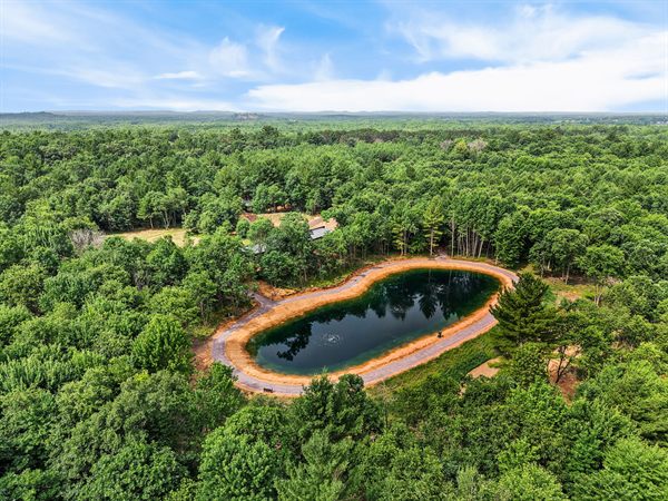 Aerial view of Oak and Ember cabins, pond, and wooded acreage
