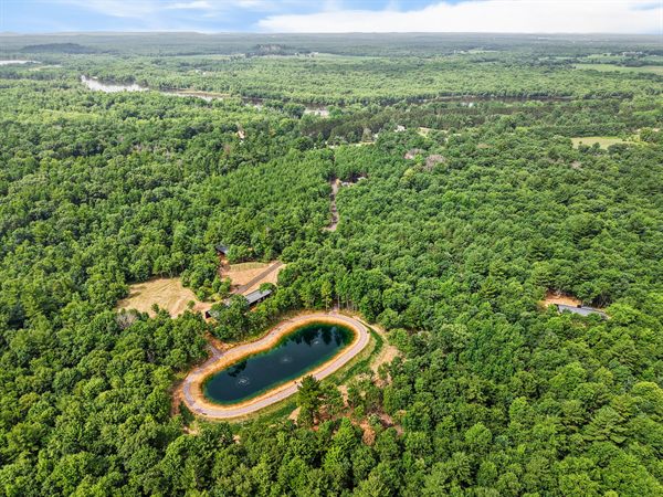 Aerial view of Oak and Ember cabins, pond, and wooded acreage