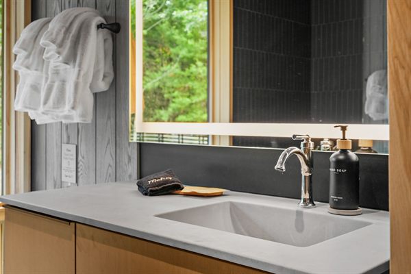 The Point modern bathroom with dark tile and warm wood vanity