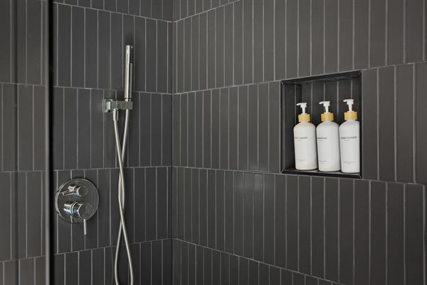 The Point modern bathroom with dark tile and warm wood vanity