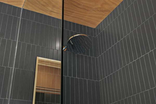The Point modern bathroom with dark tile and warm wood vanity