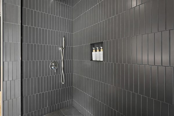 The Point modern bathroom with dark tile and warm wood vanity
