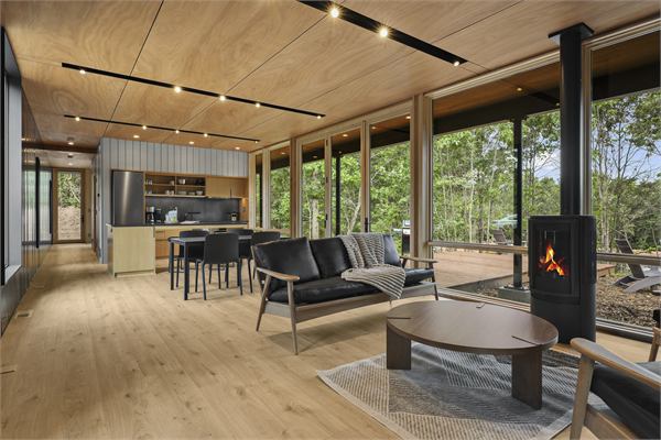The Ridge living room with gas fireplace, dining space, and wooded views